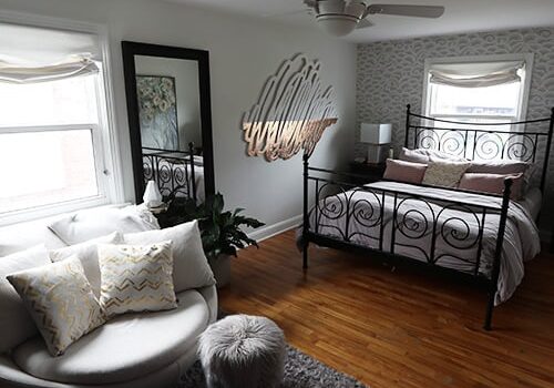 Beautiful bedroom in perfect order with hardwood flloors, wrought iron bed frame, and large loveseat.